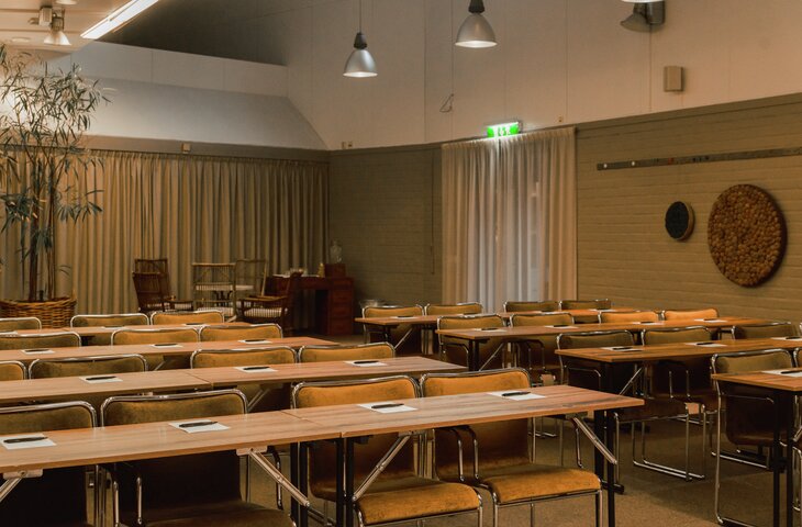 HS Dirigenten 730'480 Konferensrum med gröna stolar, träbord, projektionsskärm och blädderblock. Nödutgångsskylt synlig. Rum inrett för presentation. Hesselby Slott Hässelby nära Stockholm