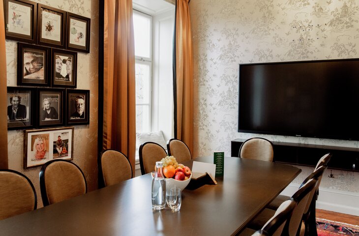 HS musikförläggaren 730'480 Mötesrum med inramade porträtt, blommig tapet, orange gardiner, stort bord, stolar, TV och fruktskål på bordet. Hässelby Slott närta Stockholm